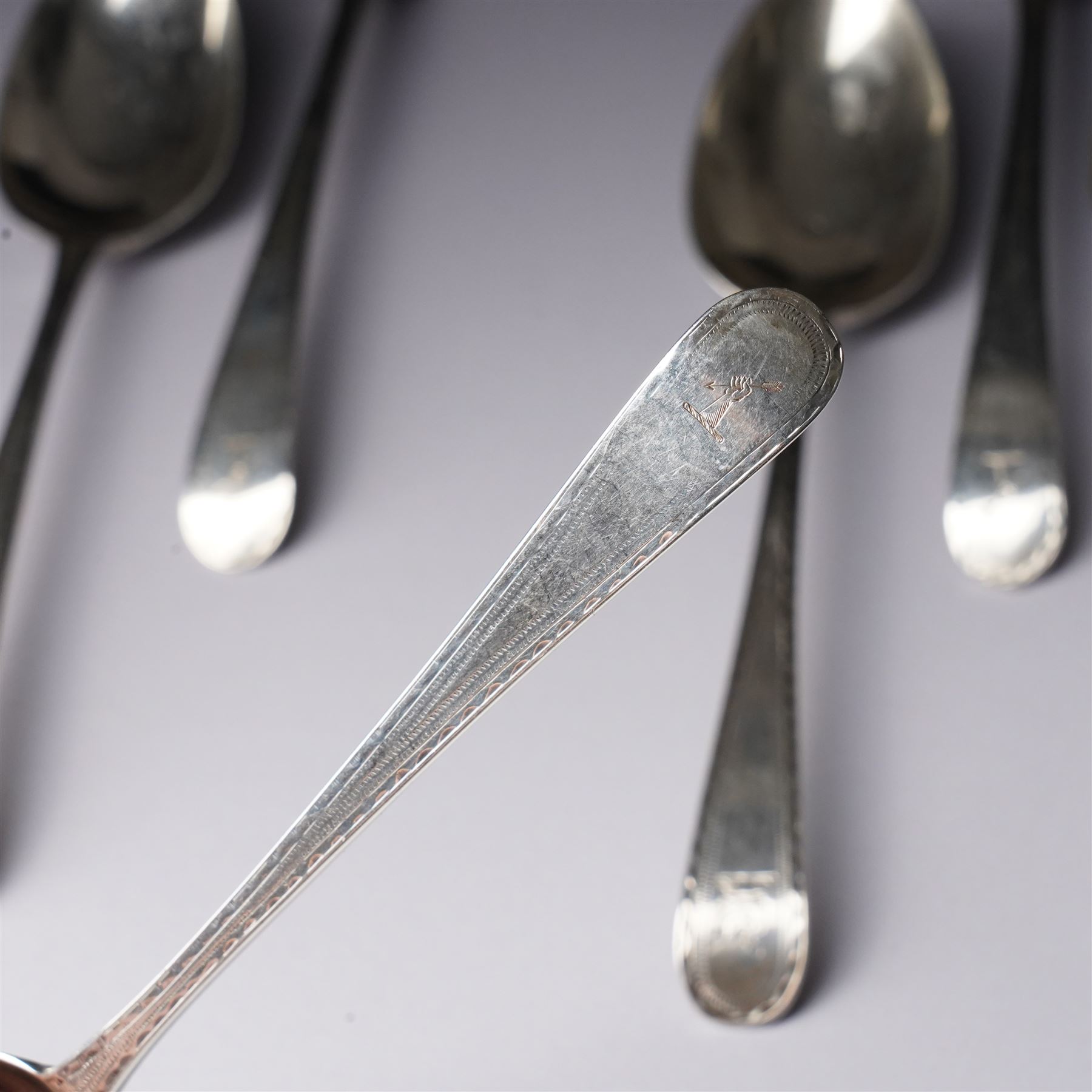 Set of six George III silver dessert spoons with bright cut stems and engraved with a crest London 1783 Maker Hester Bateman