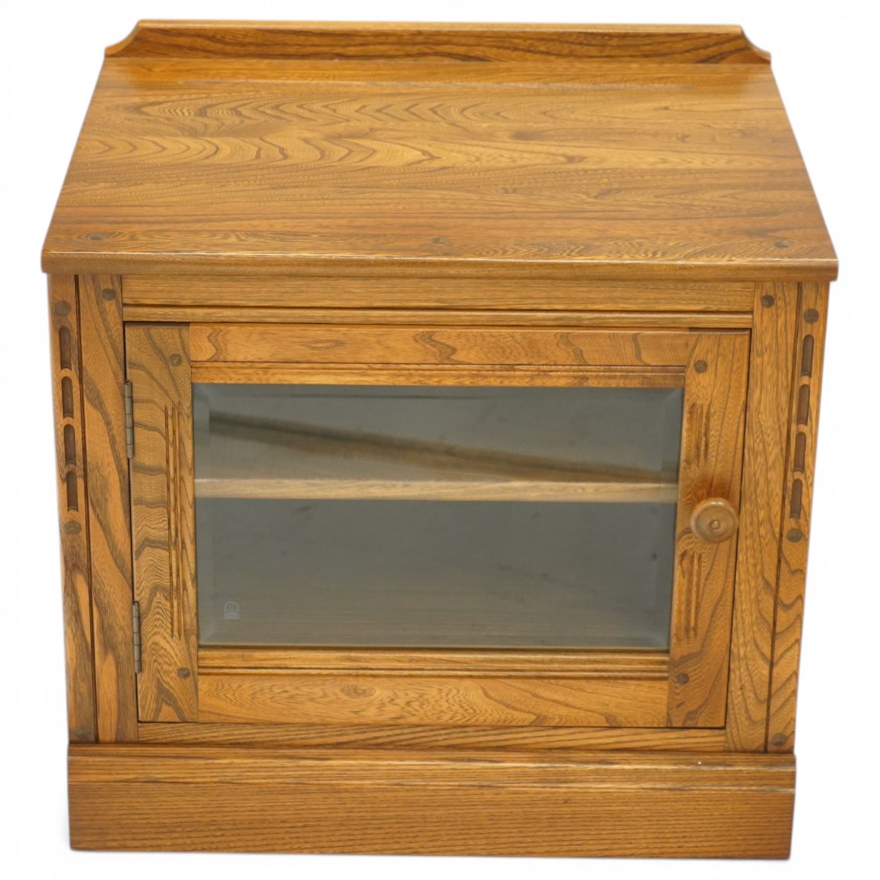 Ercol - elm media cabinet of small proportions, fitted with glazed door enclosing single shelf, on skirted base