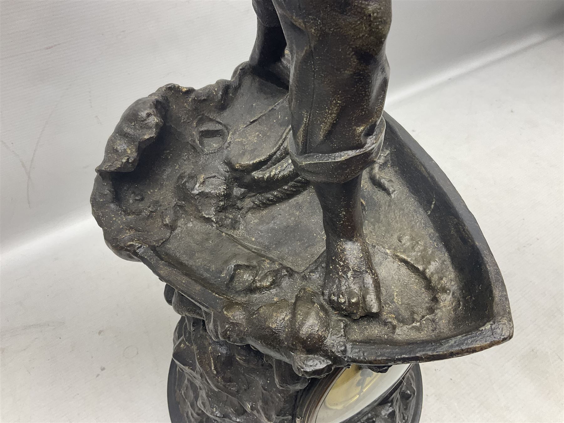 Early 20th century spelter effect figure of a sailor standing in the bow of a boat scanning the horizon, on a simulated rock base with a plaque entitled 'Rescue', base fitted with a timepiece clock movement and two-part dial, with pierced hands, gilt dial centre and ivorene chapter ring written in Arabic numerals, German HAC spring driven going barrel movement wound from the front; with pendulum H65.5cm
