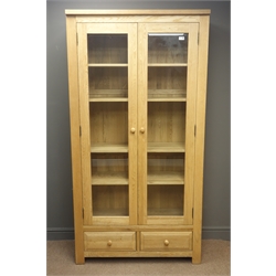  Solid oak large display cabinet, projecting cornice, two bevel eedge glazed doors enclosing four adjustable shelves, two drawers, solid end supports, W100cm, H194cm, D39cm  