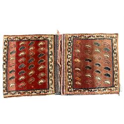 Antique Persian red ground saddle bag, decorated with all-over Boteh motifs, geometric patterned border (127cm x 68cm); Persian indigo ground saddle bag, decorated with two geometric ivory lozenges (113cm x 62cm); Persian red ground saddle bag decorated with lozenges and multi-band border (110cm x 65cm) 