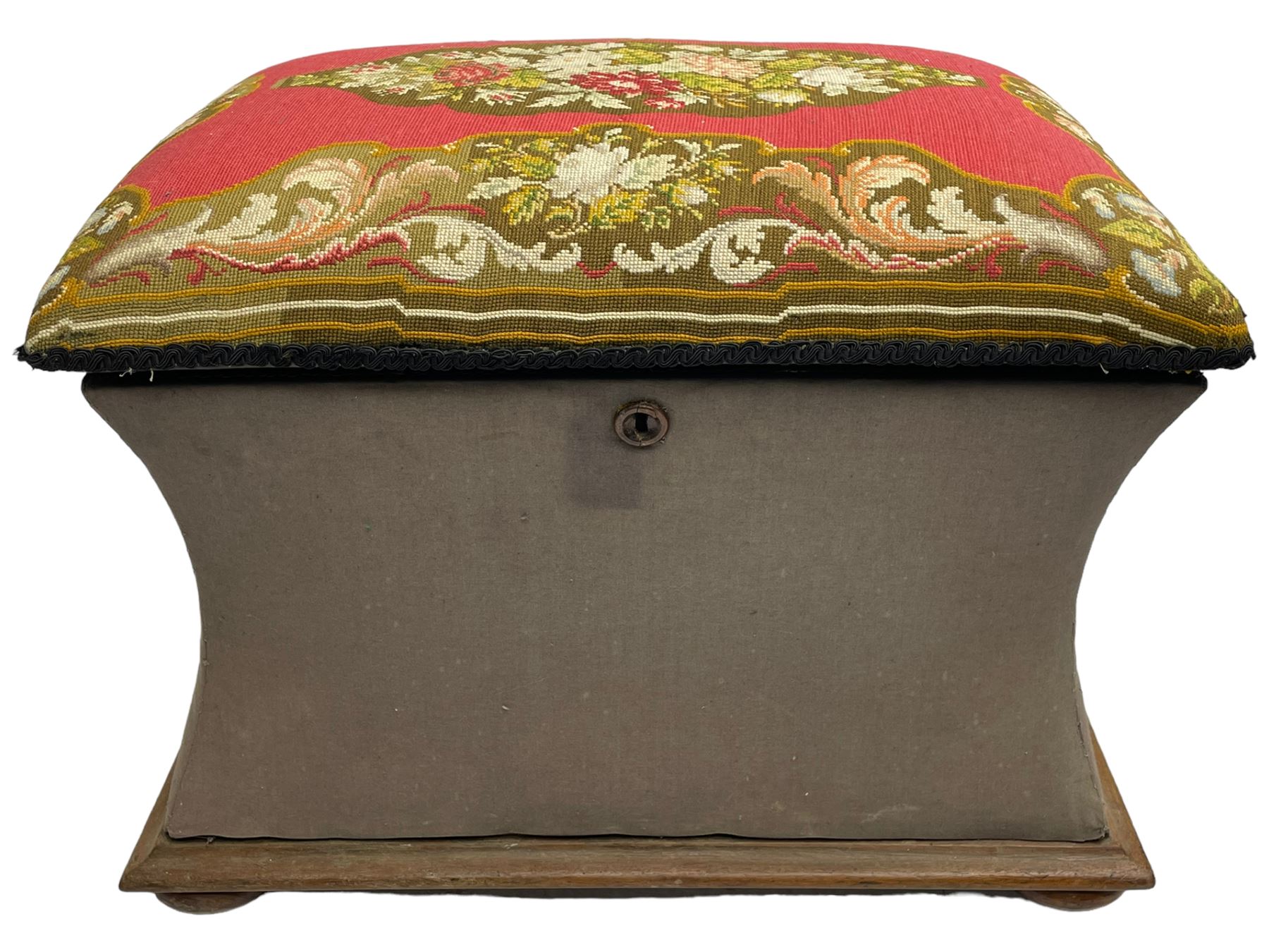 19th century upholstered ottoman, rectangular waisted form with hinged lid, upholstered in needle work cover decorated with floral panels and borders, the interior lined in blue fabric, lower moulded edge over compressed bun feet