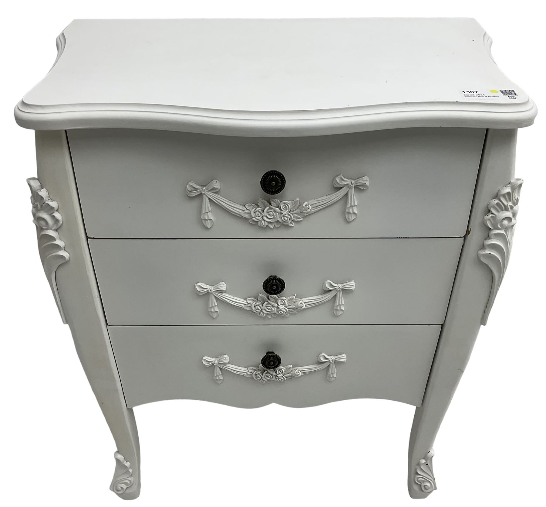 French design white painted chest, shaped top over three drawers, each with applied swags with flower heads, flanked by cabriole uprights with foliate mouldings