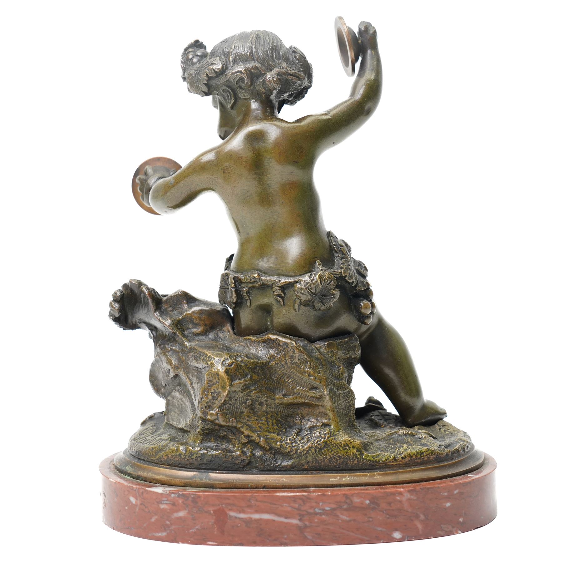 After Michel Claude Clodion (French 1738-1814): Grand Tour patinated bronze figure of a bacchic cherub, modelled dancing and playing cymbals, seated upon a naturalistic rocky base entwined with vine leaves and grapes, bearing signature, mounted on an oval red marble plinth, 19th century, W15cm H19cm