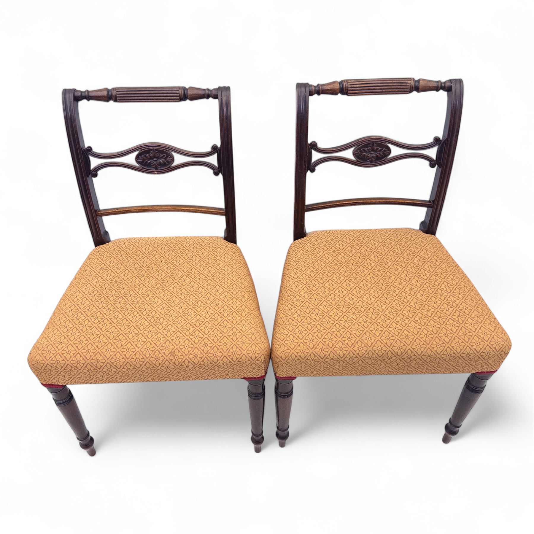 Pair of Regency mahogany side chairs, reeded bar backs centred by oval paterae, overstuffed seats upholstered in gold geometric patterned fabric, on turned tapering front supports 