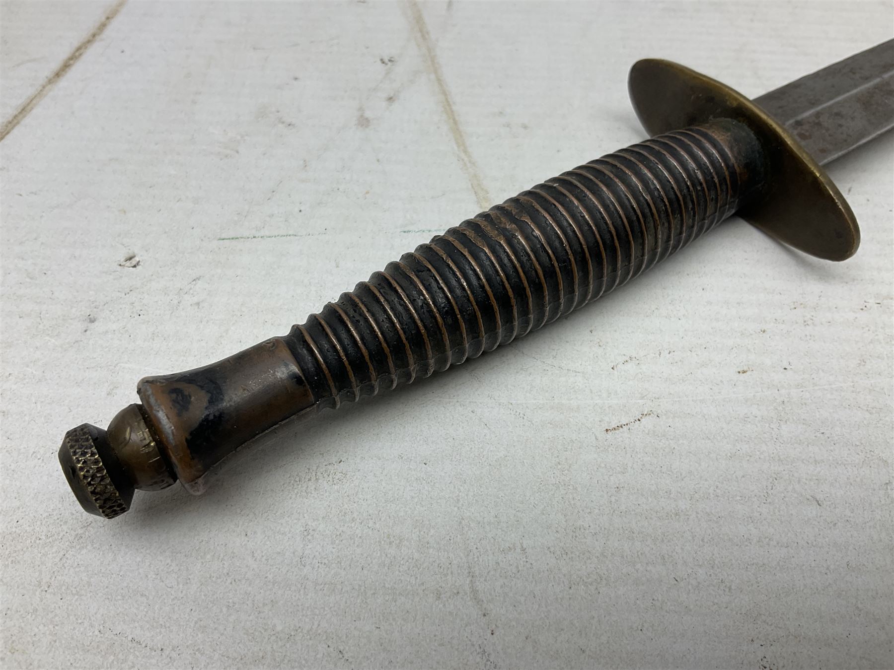 Fairburn and Sykes Commando fighting knife, 3rd pattern with 17cm double edged blade and copperised grip; no markings; in cut-down plain leather sheath L31.5cm