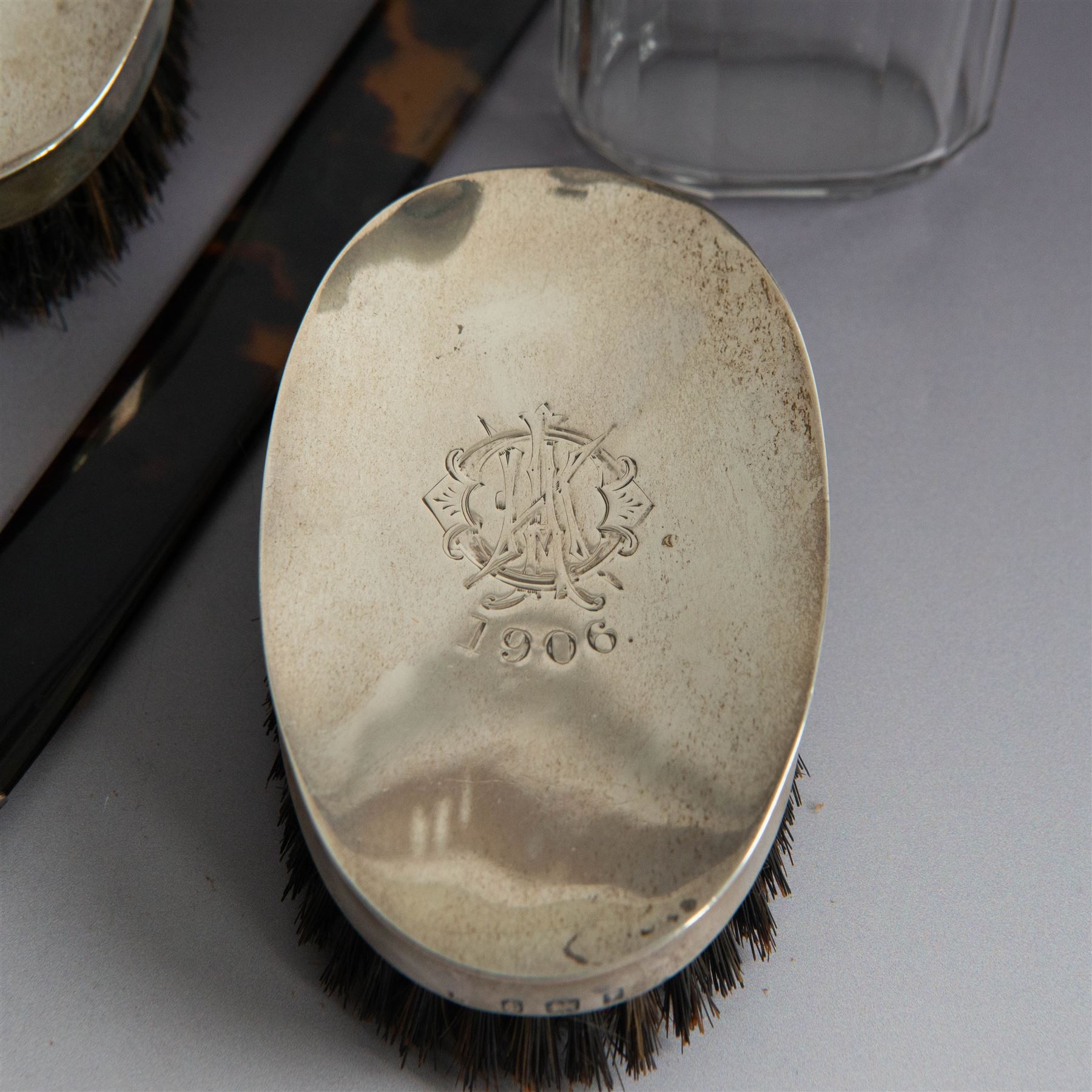 Edwardian tortoiseshell page turner with silver handle, hallmarked Birmingham 1906, maker's mark worn and indistinct, together with a pair of Edwardian silver mounted horsehair brushes engraved with monogram, and two faceted glass jars with silver lids and applied initial N to covers, all hallmarked 