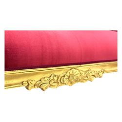 Victorian design giltwood chaise longue, the curved backrest and seat upholstered in deep red velvet with tufted detailing, the frame carved with floral motifs and scrolling acanthus leaves, raised on shaped cabriole supports