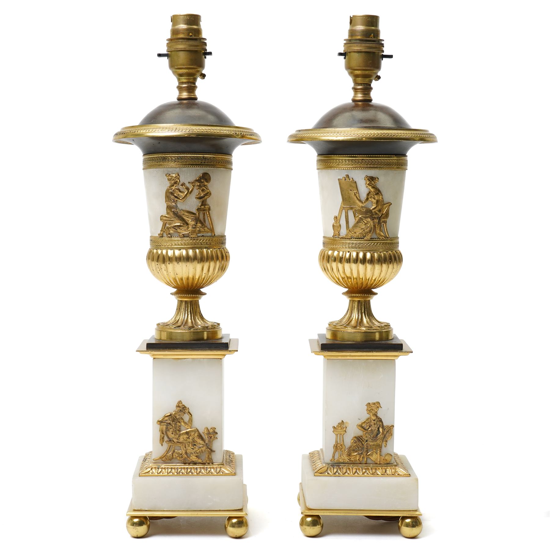 Pair of early 20th-century Neoclassical lamp bases in gilt bronze and alabaster, each decorated with classical figural reliefs celebrating the arts, each of baluster form, the alabaster bodies applied with finely cast gilt-bronze scenes including a seated painter at an easel, a sculptor at work, and allegorical female figures with musical  and theatrical motifs, mounted on square alabaster plinths with gilt-bronze borders and raised on bun feet, the domed shoulders enriched with laurel-leaf mouldings, H42cm 