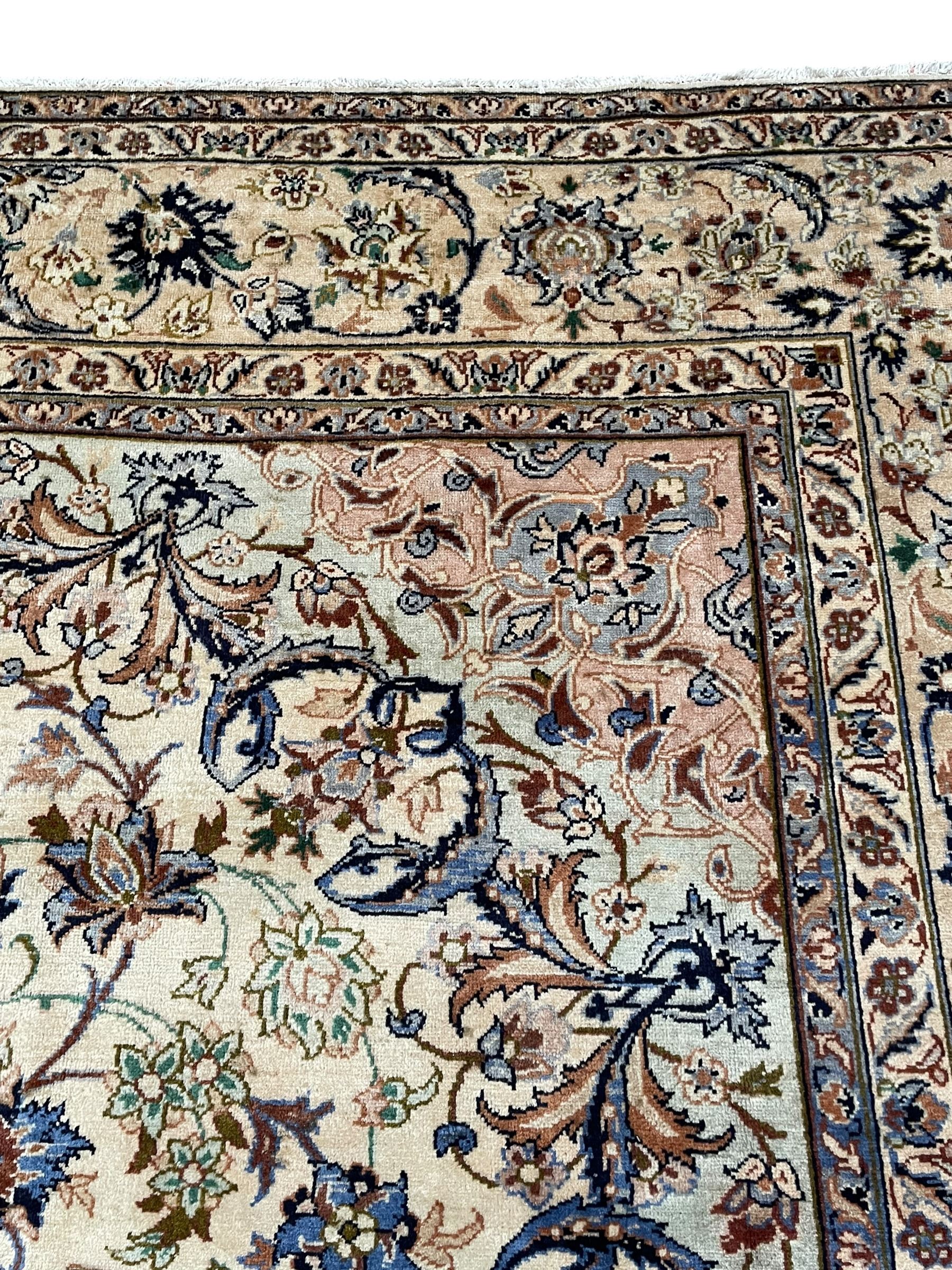 Persian Kashan ivory ground carpet, floral design central medallion surrounded by trailing and interlaced leafy branches with palmettes and flower heads, matching patterned border with guard stripes 