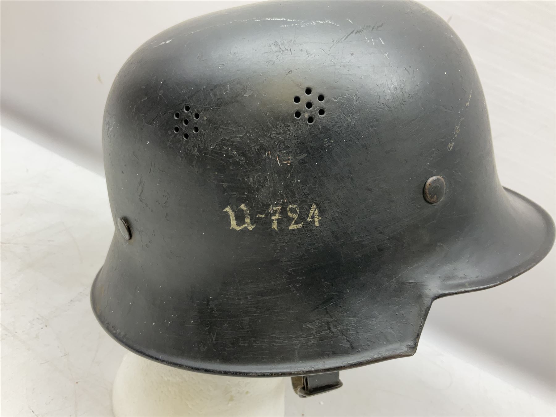 WW2 German steel combat helmet with eagle insignia to one side and U-724 to the other, leather liner marked No.56 and leather chin strap; indistinctly stamped to the skirt '*ahl'