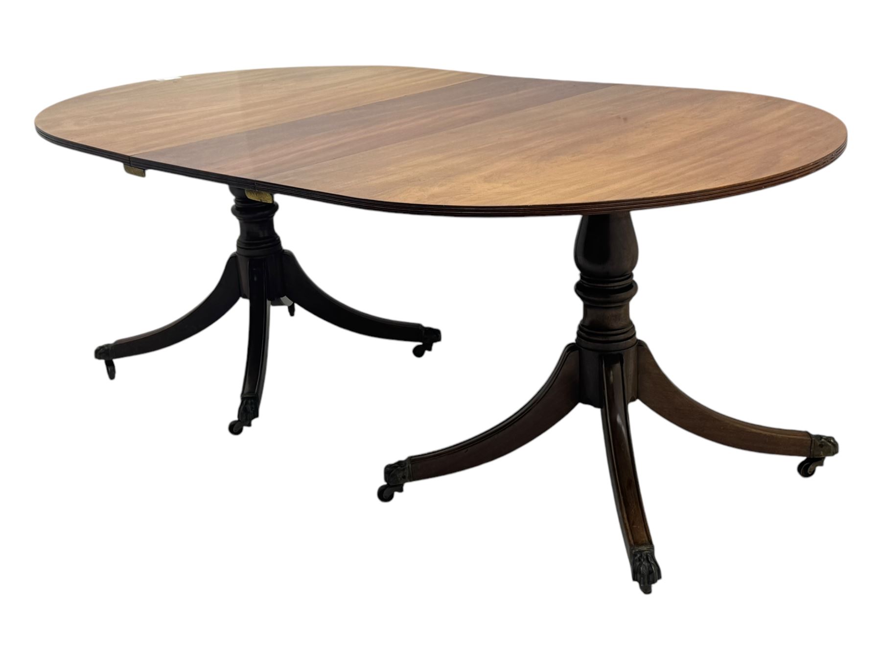 Georgian design mahogany twin pedestal dining table, oval top with reeded edge, single additional leaf, on turned pedestal with four out splayed supports, cast brass hairy paw castors 