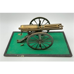 Scratch built brass model of an 1861 Gatling Gun with rotating barrels, hinged cover revealing mechanism, on metal bound wooden spoked wheels and rectangular base L47cm H22cm