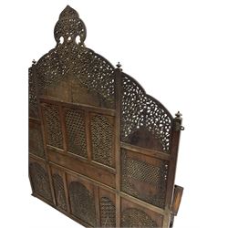 Late 19th century Indian Burmese carved and pierced hardwood and brass inlaid wall shelf, the shaped back profusely decorated with trailing and interlaced foliage, with projecting architectural structures, the central balcony with canopy top and five open windows with arched apertures on columns, two flanking five-sided balconies, the shelf supported by six foliate carved columns with pierced cusped pointed arches 