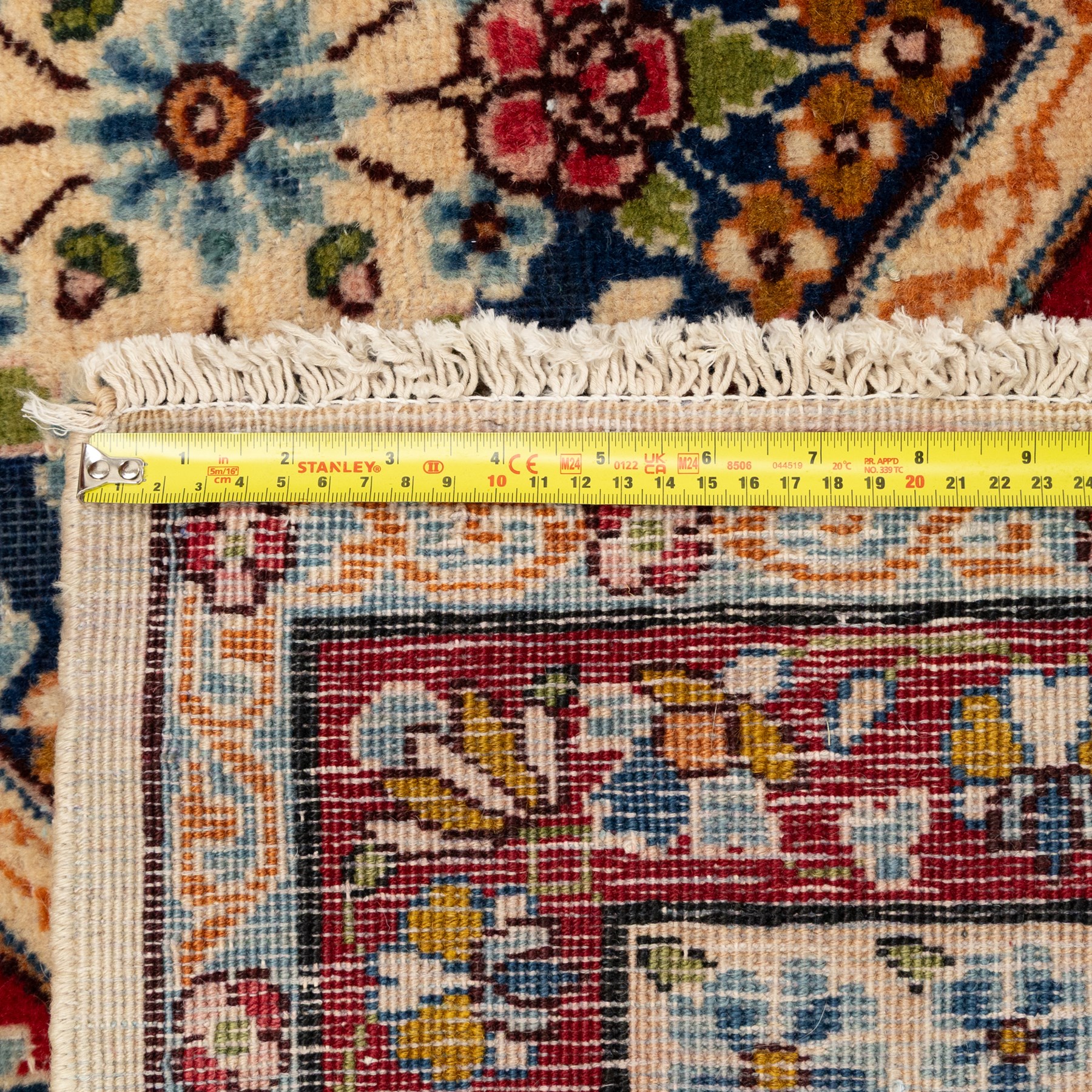 Central Persian Kirman carpet, the field arranged with alternating indigo star shaped and red cruciform compartments, each filled with rosettes, flowerheads and scrolling foliage, enclosed by a broad ivory palmette border and red floral guard bands