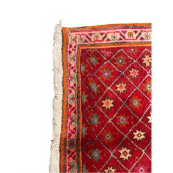 Persian Shiraz red ground rug, the field intersected with criss-cross lines and decorated with star motifs, the border decorated with flower head motifs