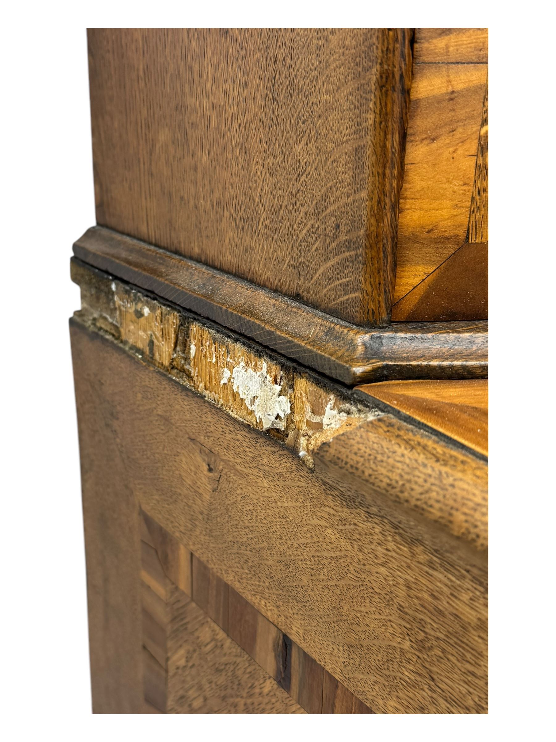 Late 19th century continental oak commode, serpentine fronted with parquetry and crossbanded decoration, the raised superstructure back fitted with a central bank of five recessed drawers flanked by concave drawers, above three full-width drawers with brass ring handles, raised on cabriole supports