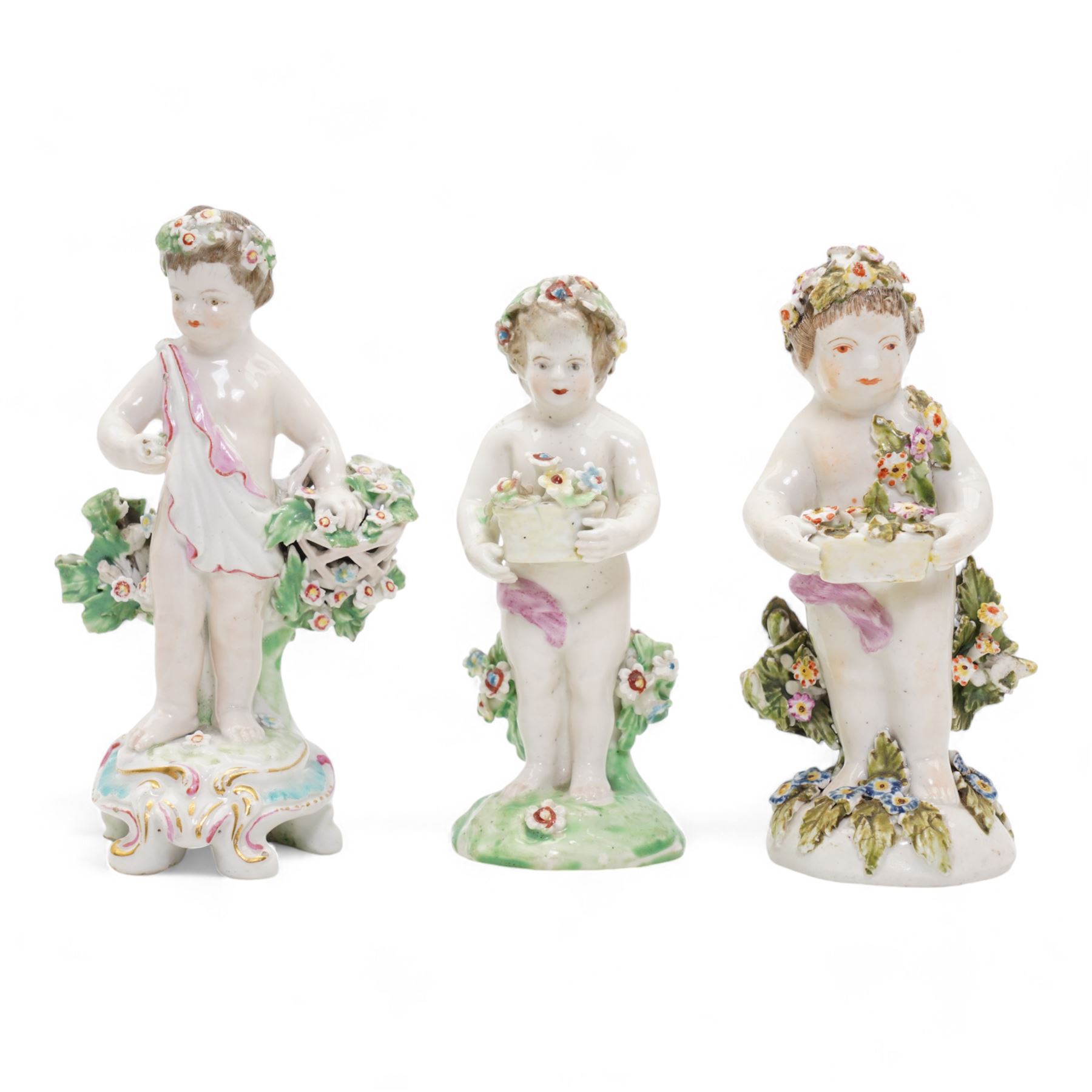 Derby porcelain model of a cherub holding a basket of flowers and wearing a chaplet, H13cm, another Derby cherub holding a basket of flowers and another Derby style cherub, together with a 19th century Staffordshire Ralph Wood type pearlware figure emblematic of Autumn, holding grapes and a goblet (4)