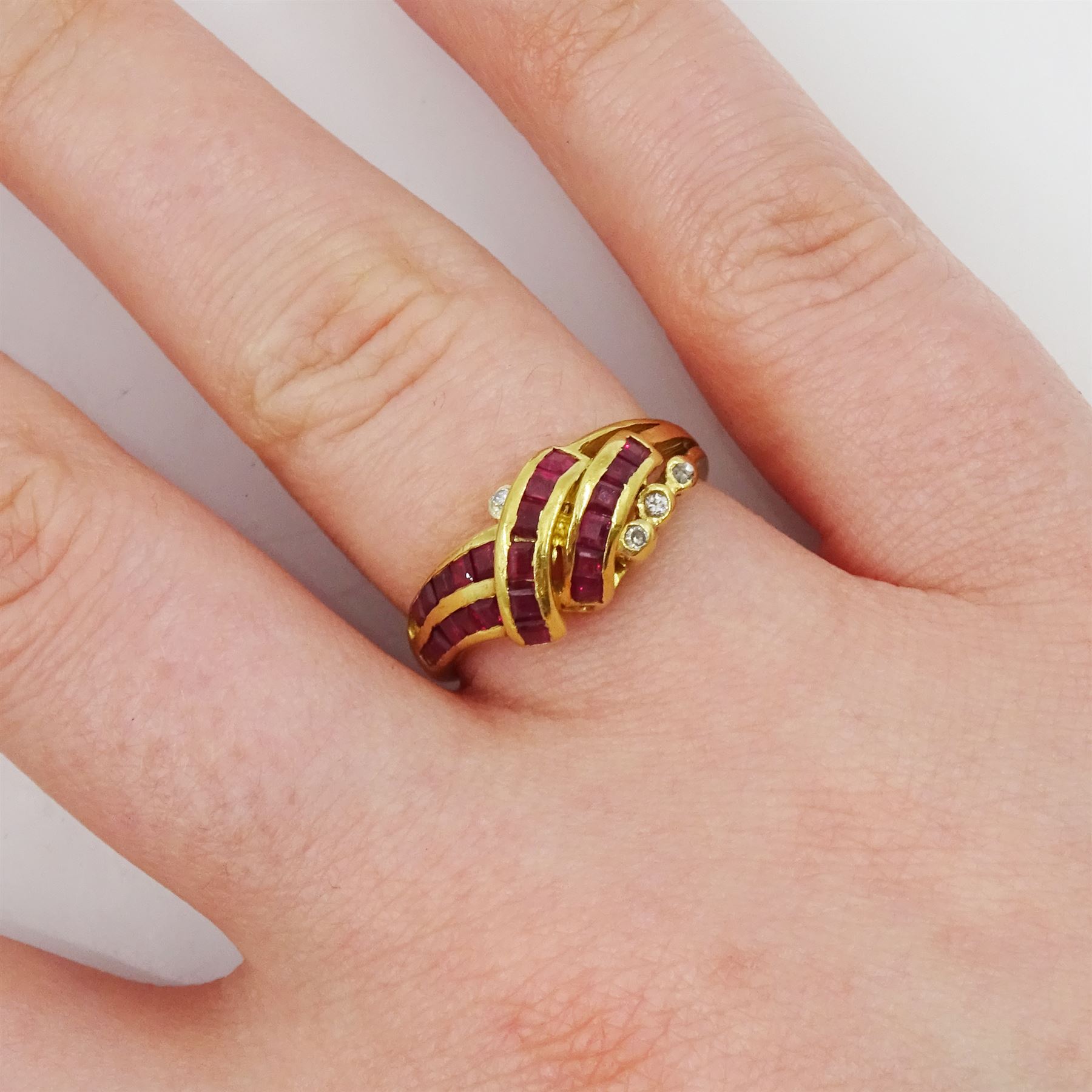 18ct gold channel set, calibre cut ruby and round brilliant cut diamond crossover ring, stamped 750