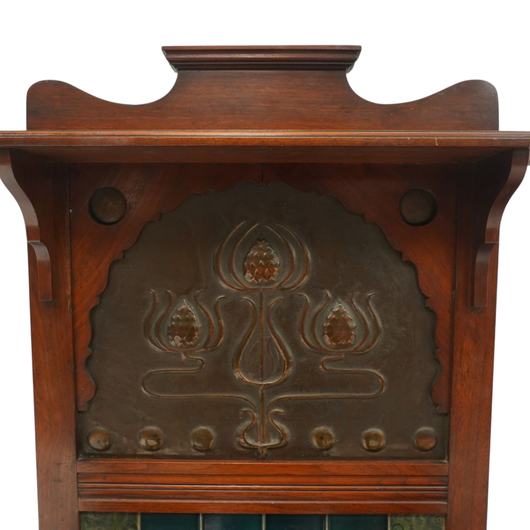Shapland & Petter of Barnstaple - Arts & Crafts mahogany tile-backed umbrella or stick hall-stand, model no.114, the shaped back with single shelf over an Art Nouveau embossed patinated copper panel and turquoise tiled back, with turned supports and dividers over inset metal drip tray

Notes: A comparable Shapland & Petter stick stand of this model is recorded in Daryl Bennett, Shapland & Petter Ltd of Barnstaple, Museum of Barnstaple and North Devon, p.84, cat. no.5.37, and the model is also listed in Bennett, Liberty’s Furniture 1875-1915, p.298, cat. no.8.6. Examples of this model are known to have been retailed by Liberty & Co.