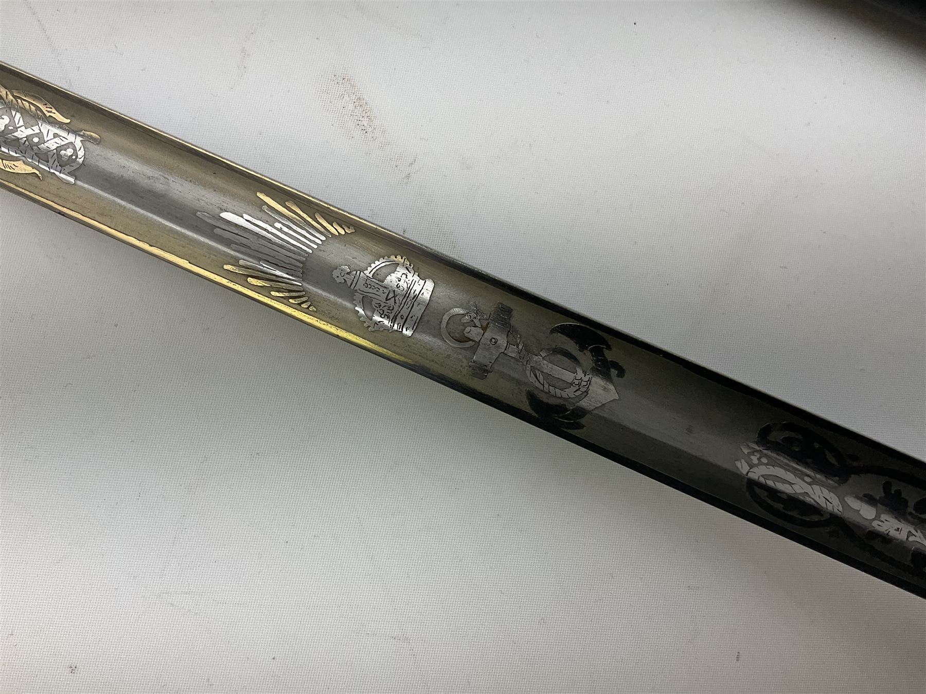 WW1 George V era 1827 Pattern Royal Naval Officer’s sword, the 80cm fullered steel blade decorated with crown, fouled anchor etc and marked Gieves Portsmouth London Edinburgh Devonport to the ricasso, gilded hilt with fouled anchor and crown, wire-bound ray skin grip, lion’s head pommel with mane backstrap, folding/locking langet and full bullion knot; in  leather scabbard having twin brass lockets with hand engraved panels and twin suspension rings L94cm overall. Provenance: By direct family descent from Brian Heathcote HMS Conqueror later Superintendant in the Liverpool Special Constabulary.