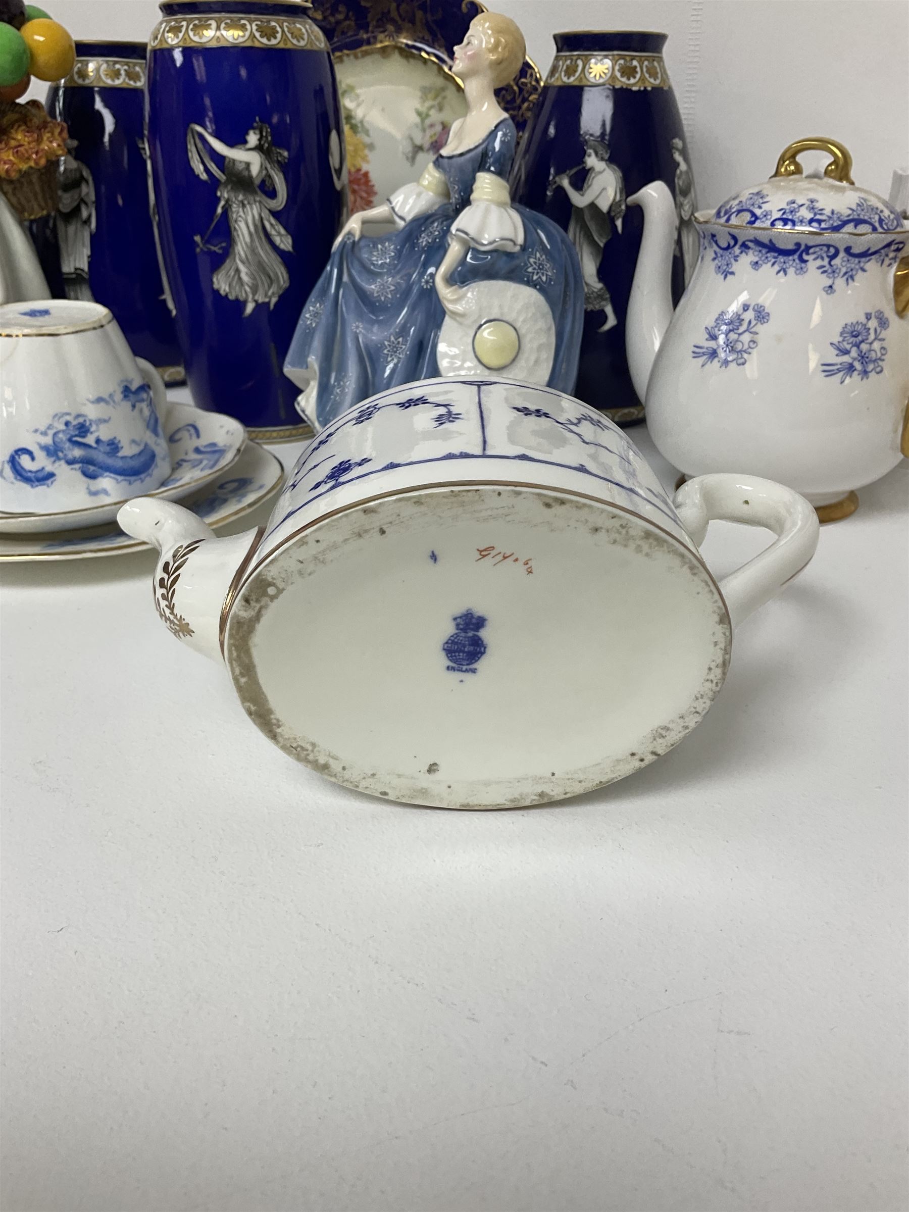  Mintons teapot of oval form, circa 1900, decorated in blue with foliate sprigging within gilt borders upon white ground, Shelley Heavenly Blue teapot, together with another Shelley teapot decorated with berries and foliage, two Royal Doulton figures comprising Biddy Penny Farthing HN1843 and Hilary HN2335, pair of Spode's New Stone plates, etc