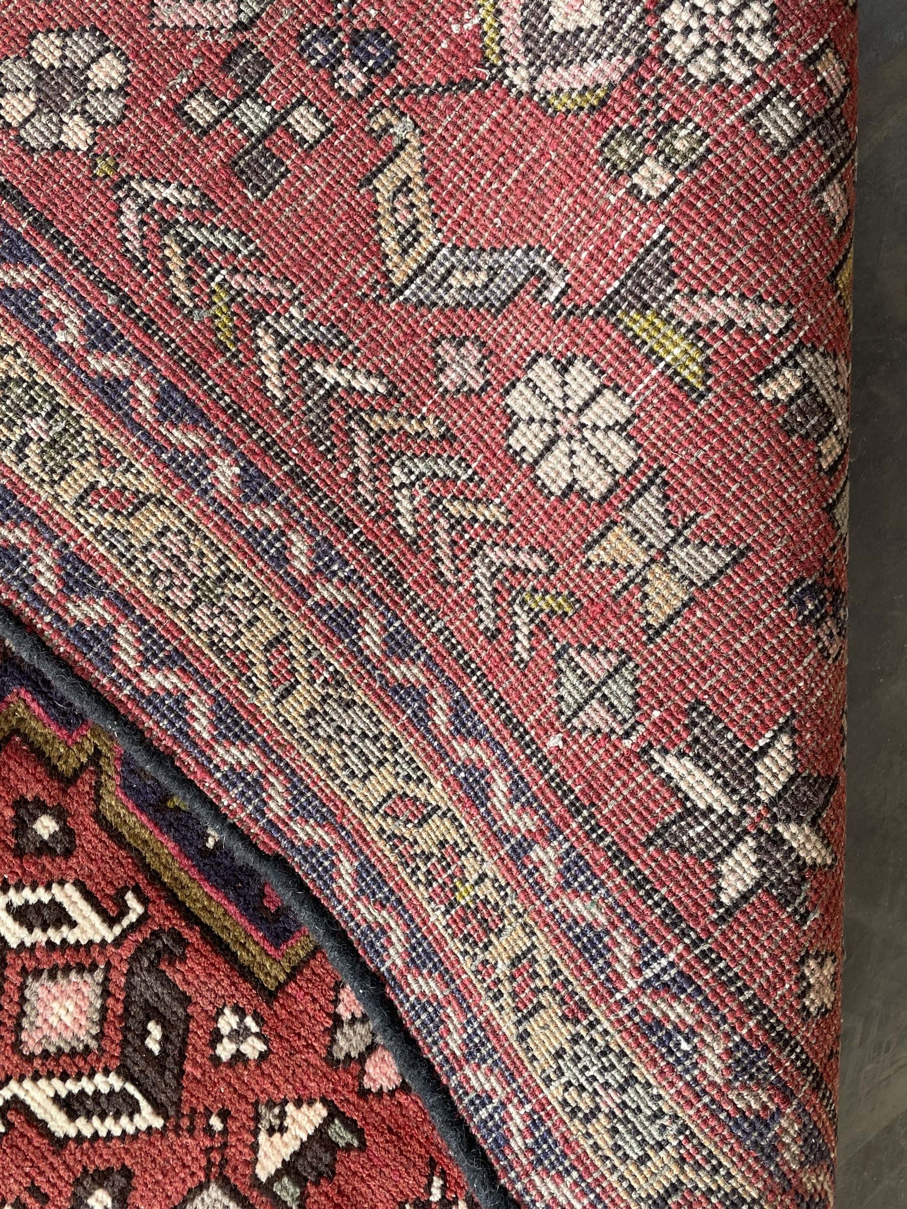 Persian Karajeh red ground runner, decorated with multiple stylised medallions and motifs