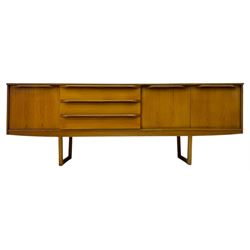 Mid-20th century teak sideboard, fitted with a fall-front cupboard, three drawers including a green baize-lined cutlery drawer, and a double cupboard, with integrated handles, on sleigh supports