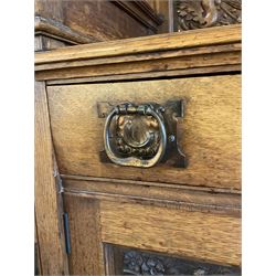 Late 19th century Arts & Crafts period oak mirror back sideboard, shaped bevelled mirror back carved with foliate scrolls and flower heads, down swept supports with elongated club-shaped uprights, moulded rectangular top over two drawers and three cupboards, the drawer fronts with copper handles decorated with sailing ships, panelled doors carved with mythical beasts, flowerheads and foliage, on moulded block feet