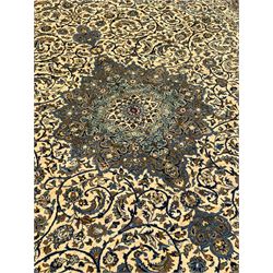 Persian Meshed carpet, ivory ground and decorated with intricate floral design with trailing scrolled branch, the central medallion decorated with stylised plant motifs, seven band border, the main band decorated with scrolls and flower head motifs