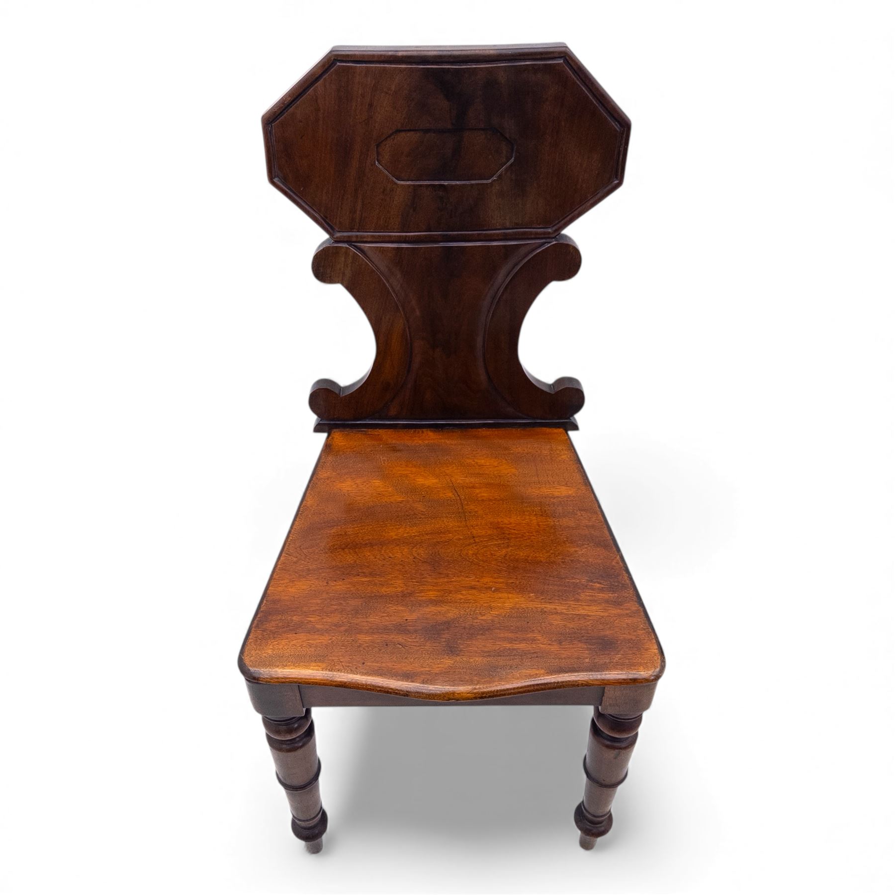 Pair of 19th century mahogany hall chairs, each with shaped octagonal backrest featuring a recessed cartouche panel, serpentine supports and moulded seat, raised on turned front legs