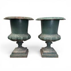 Pair of Victorian cast iron campana garden urns, the flared rim with repeating stylised anthemion motifs with scrollwork, over a deep gadrooned and Aesthetic moulded underbelly, fluted and foliate lower bowls on square pedestal bases, in antique green-painted finish