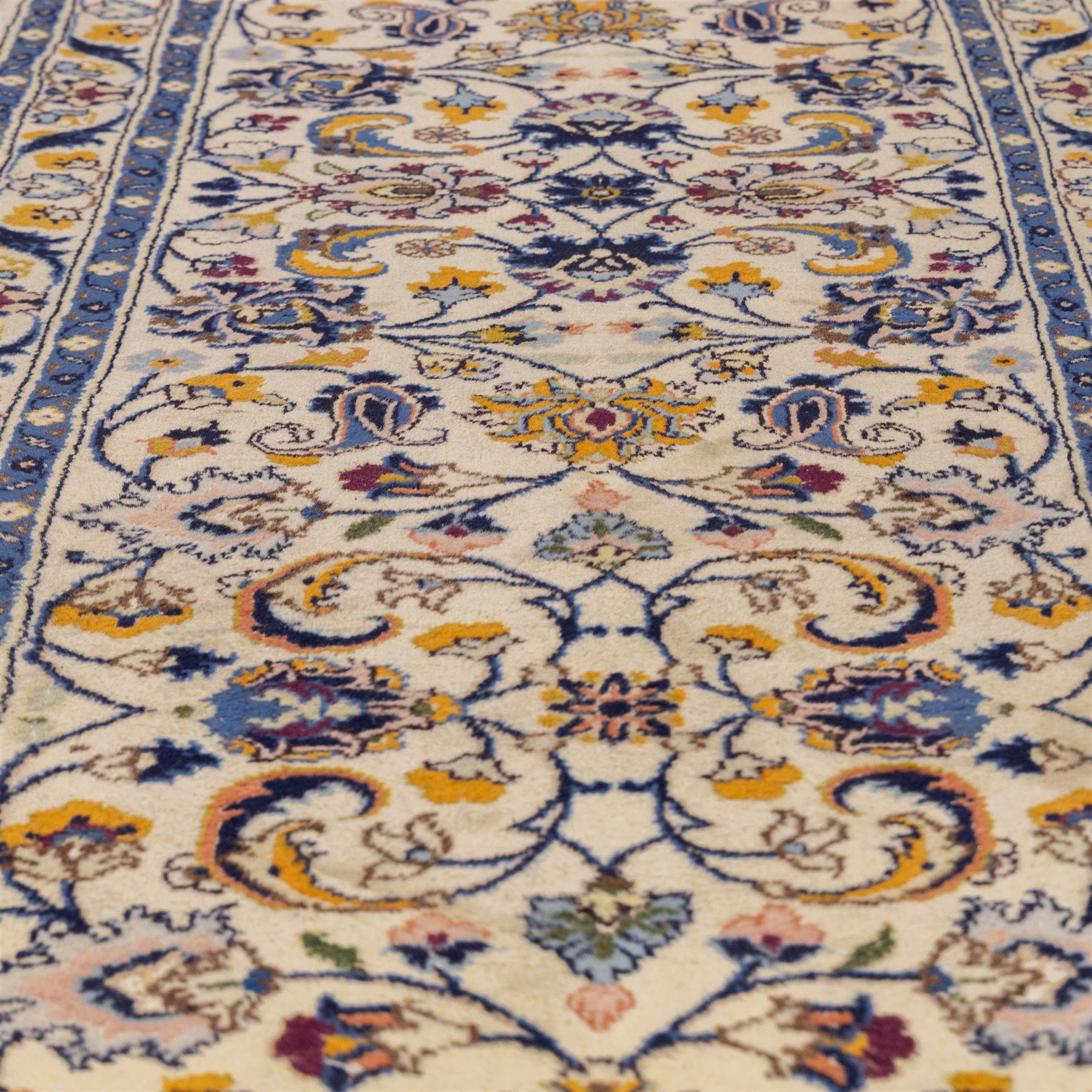Central Persian Kashan hand-knotted runner, ivory field decorated with an elegant all-over scrolling vine design composed of finely drawn palmettes, floral strays and arabesques in a continuous lattice, principal border on an indigo ground decorated with palmette and vine scroll, flanked by multiple narrow guard stripes, with cotton fringe ends 