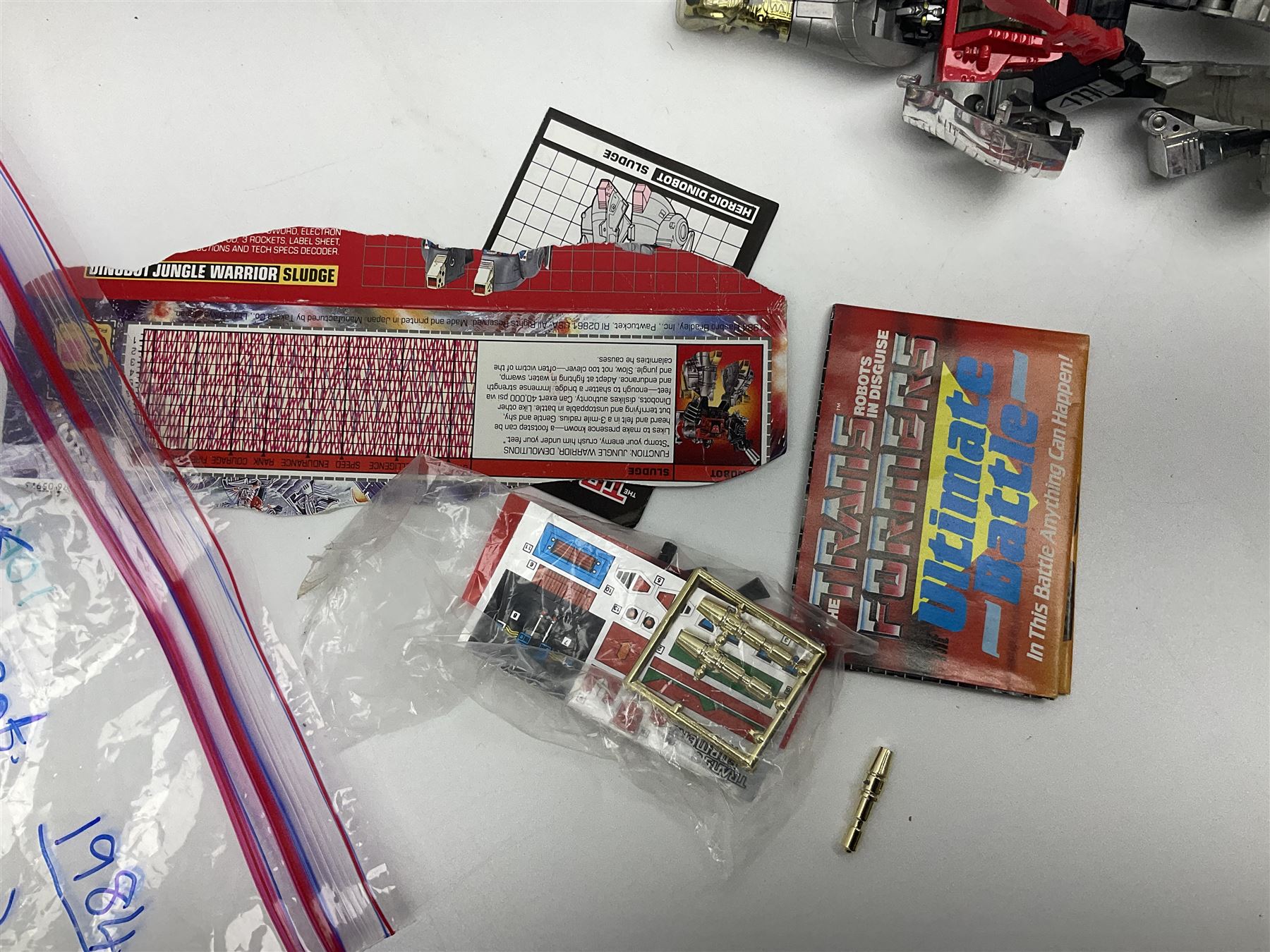 Four 1980sTransformer G1 - Optimus Prime 1984; DinoBot Sludge (Diplodocus) 1984; Cyclonus 1986; and Runamuck 1986; with paperwork; seven Bandai Robo Machines Robots/Transformers; almost fully stocked Panini Sticker album; two annuals; three comics; two posters; and Ladybird story book