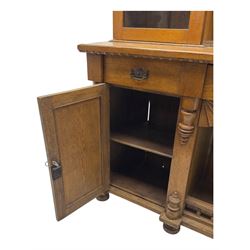 Late 19th century pine dresser, the projecting cornice with dentil and spindle moulded frieze above a three-tier plate shelves, flanked by glazed doors, the base fitted with three frieze drawers over arched apron and carved floral panelled cupboard doors, raised on turned feet