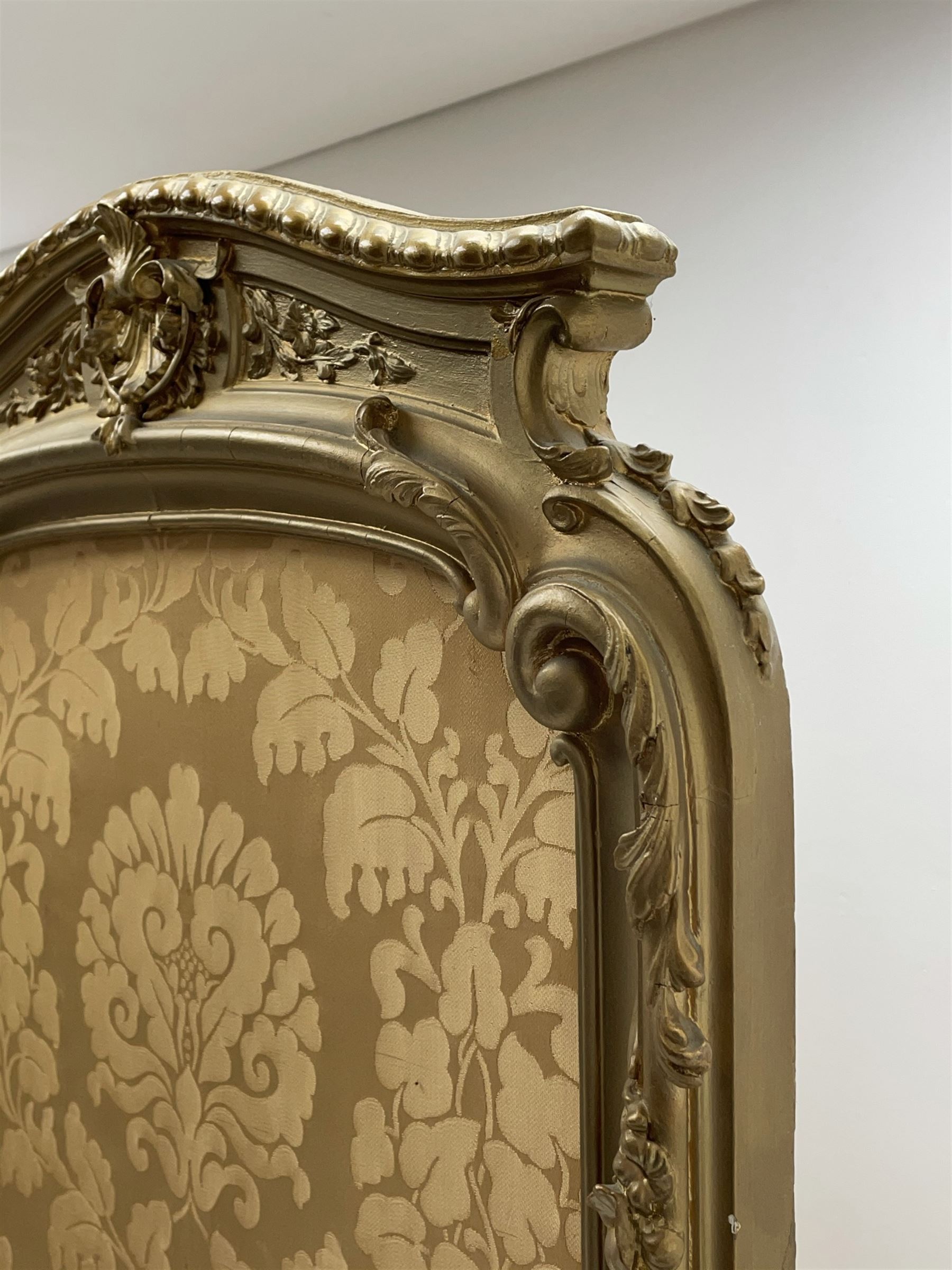 Late 19th/early 20th century French Rococo style gilt wood and gesso dressing screen, four double hinged panels, each with shaped cresting rail over shell and floral frieze, moulded frame with flower head and scroll decoration, acanthus leaf cabriole supports with castors, upholstered in gold Damask fabric