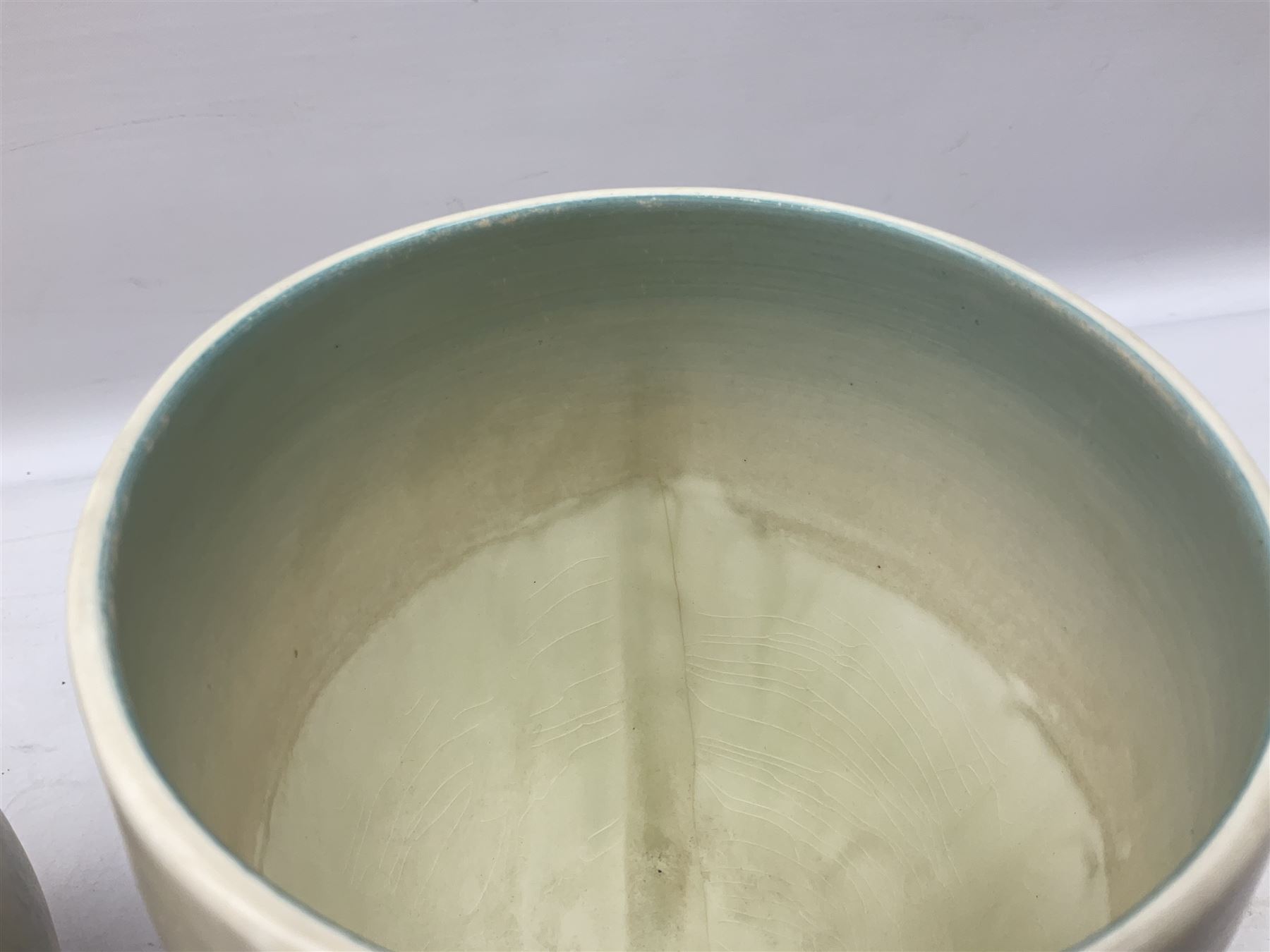 1930s Carlton Ware Art Deco Garden pattern vase of shouldered ovoid form, decorated with blue, pink and yellow flower heads on a mottled blue and white ground, pattern no. 3413, with printed and painted marks beneath, H19cm, together with a Clarice Cliff My Garden pattern vase, raised upon three feet with blue, pink and purple moulded Hollyhock design, H20cm, with Clarice Cliff Wilkinson Ltd England marks beneath