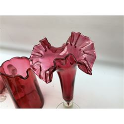 Group of cranberry glass, to include trumpet vases, with crimped decoration, jug with a clear glass handle, large vase with clear feet and crimped rim, and two ruby glass beakers