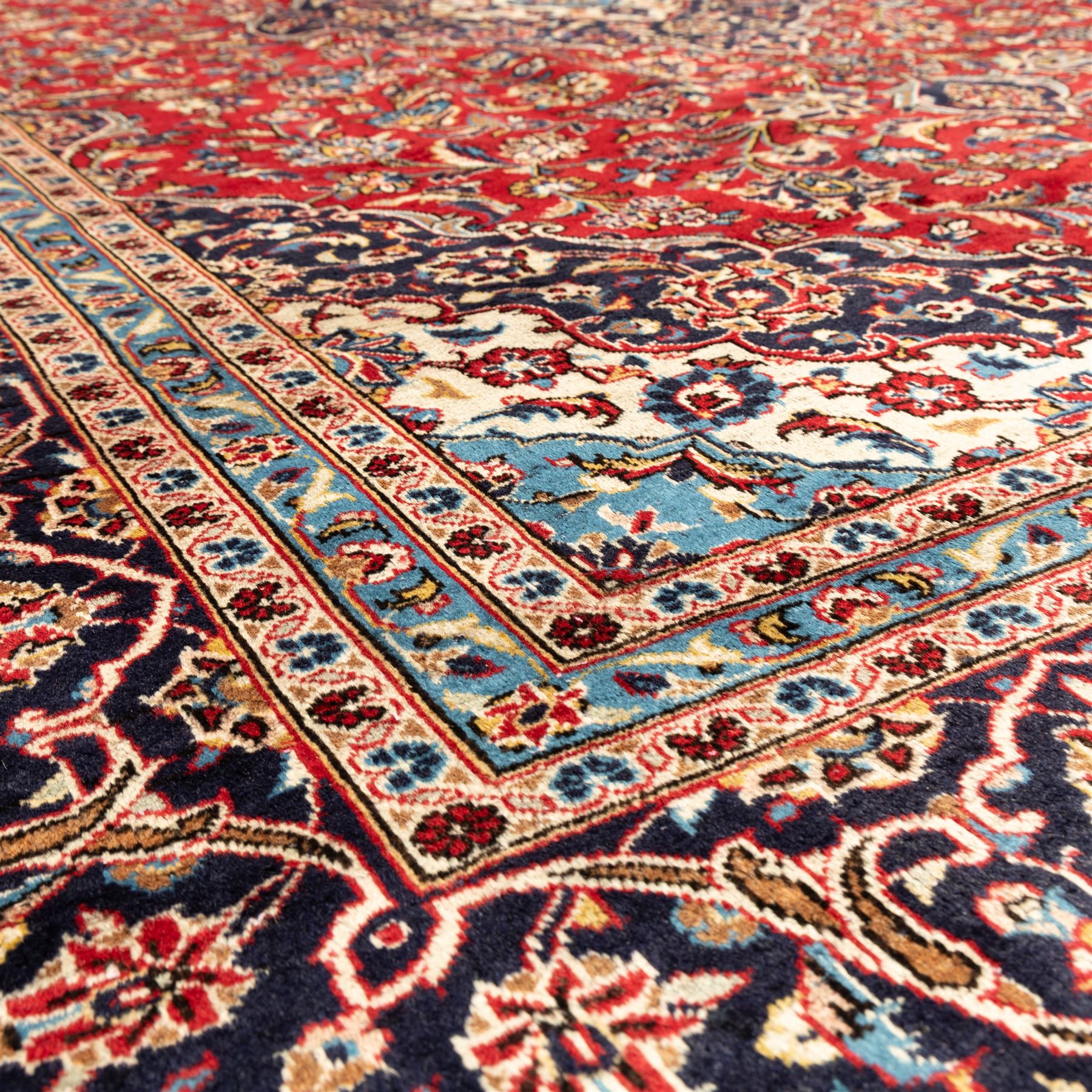Persian Ardakan carpet, brick red field with ivory and navy central medallion, surrounded by stylised lotus blossoms and cloudband motifs, framed by rich indigo borders featuring palmettes, serrated leaves and angular vine work, woven in the city of Ardakan in central Iran