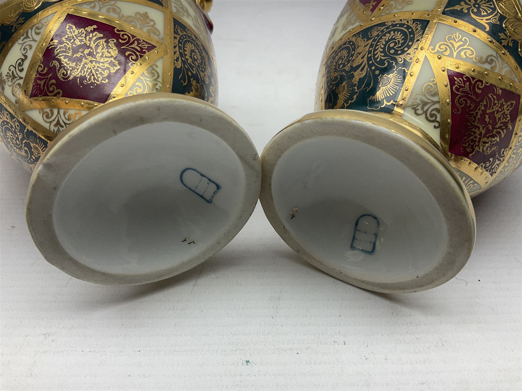 Pair of Vienna style twin handled urns and covers, decorated with figural scene on green, red and white ground with gilt highlights, stamped with beehive mark beneath, H25cm