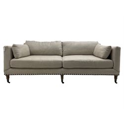 Grande three-seat sofa, traditional shape, upholstered in textured grey fabric, on turned supports with castors