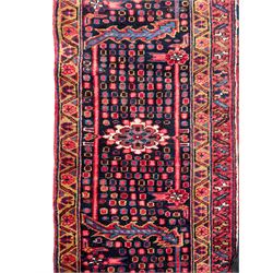 Antique Persian coral ground carpet, the large central floral pole medallion with extending foliate designs, the thick guarded indigo border with repeating flower heads and circles