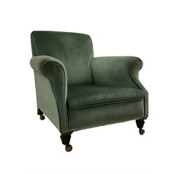 Early 20th century upholstered armchair, deep seat with curved arms, on turned mahogany feet