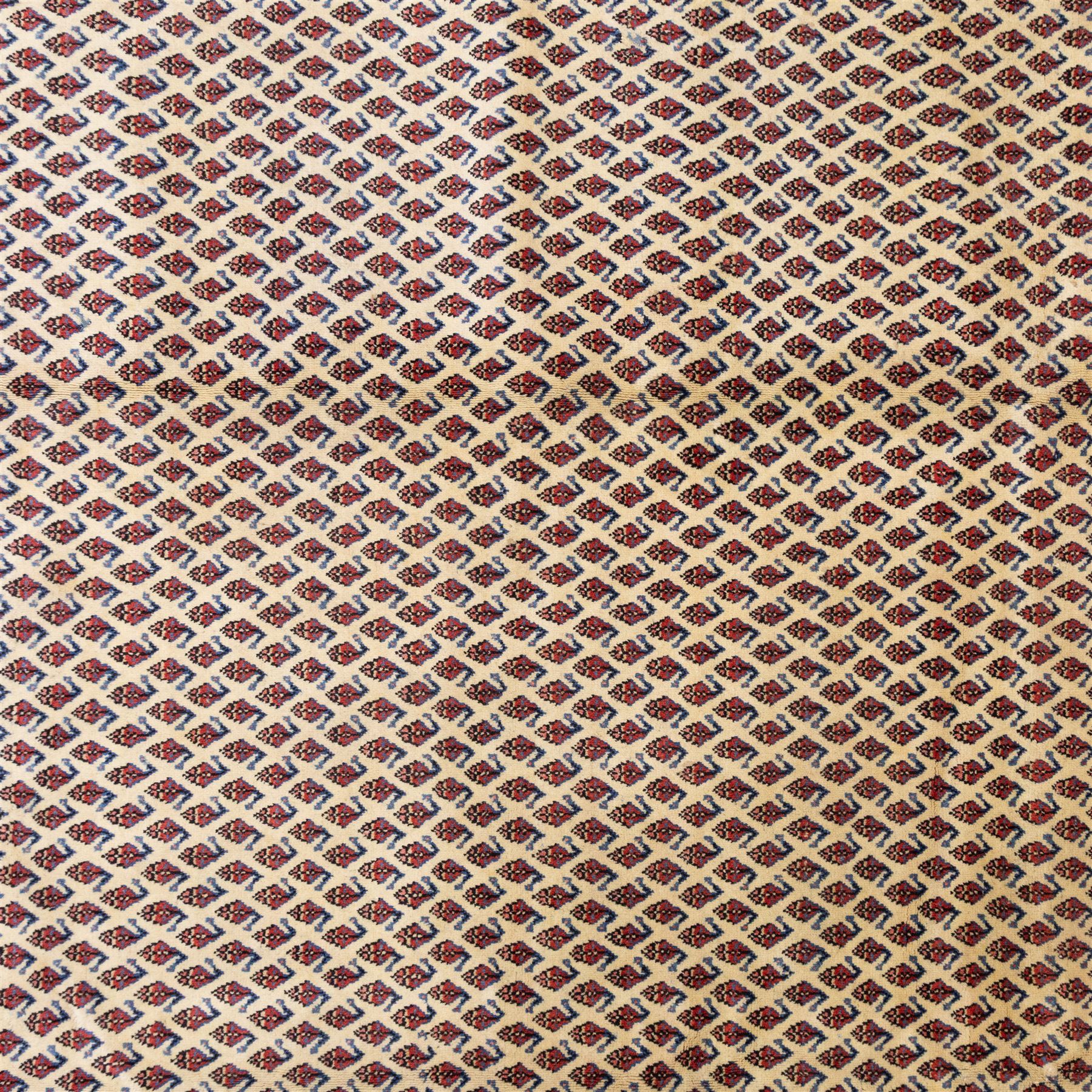 North West Persian Boteh-Mir hand-knotted rug, madder red field decorated with an all-over lattice of small boteh motifs and a central stepped lozenge medallion with repeating stylized boteh and geometric devices, spandrels similarly worked, with multiple narrow borders of floral and geometric bands, in tones of madder red, indigo blue, ivory, and soft green, with cotton fringe ends
