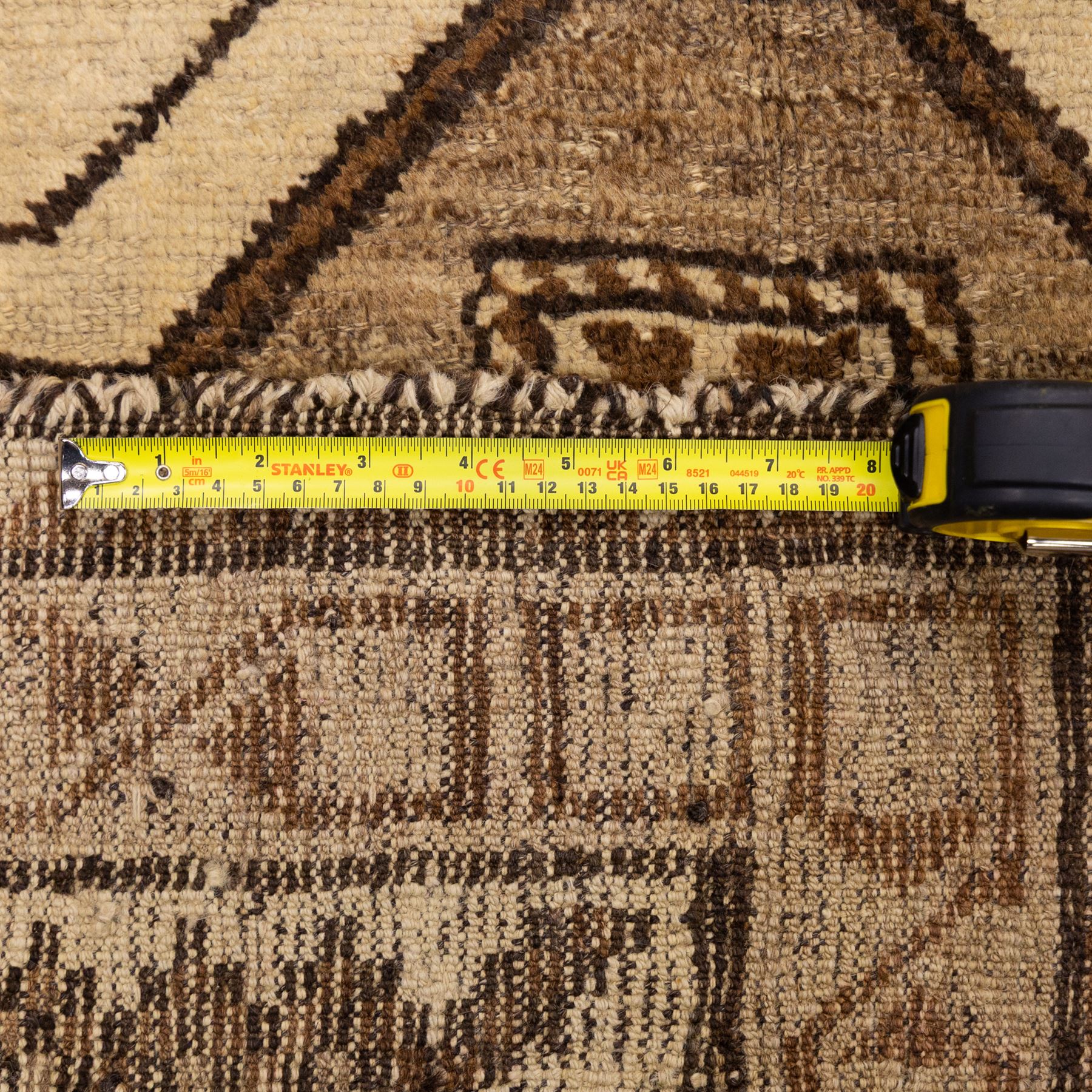 North West Persian Gabeh hand-knotted rug, natural ivory field with a vertical sequence of three large stepped geometric medallions in soft shades of brown and taupe, each enclosing stylized tribal motifs, flanked by narrow guard borders incorporating chevron and zigzag designs, with fringe ends 