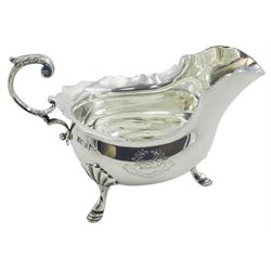 Edwardian silver sauce boat, with shaped rim and acanthus capped flying scroll handle, the body engraved with boar's head crest, upon three shell mounted hoof feet, hallmarked Walker & Hall, Sheffield 1902, including handle H9.5cm, approximate weight 6.46 ozt (201 grams)