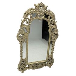 Large pale gilt finish ornate wall mirror, in scrolled foliate frame decorated with flower heads, plain mirror plate