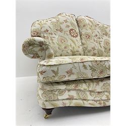 Pair traditional shaped two seat sofas upholstered in floral pattern and cream ground fabric, turned front supports with brass castors 