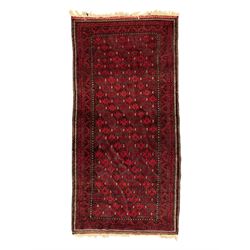 Turkoman red ground wool rug, the field with a repeating pattern of Tekke gul motifs in dark brown and red (195cm x 98cm); Afghan Bokhara red ground wool rug, central field with repeated geometric octagonal gul motifs, surrounded by multiple borders with stylised diamond and triangular patterns (127cm x 181cm)