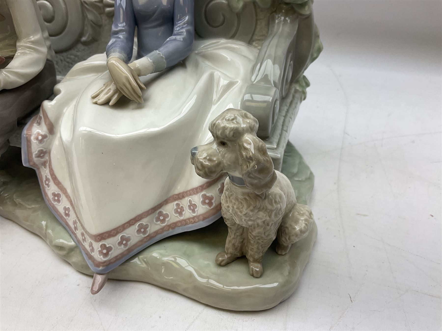 Lladro figure, Poetry of Love, modelled as a boy seated reading from a book next to a girl on garden bench with a dog at her feet, sculpted by Regino Torrijos, with original box, no 5442, year issued 1987, year retired 1998, H22cm